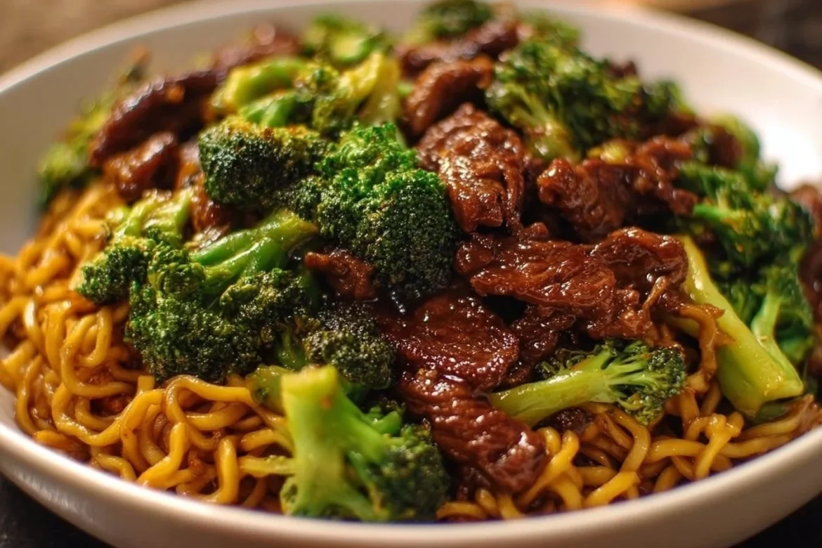 Plate of Chinese Crispy Beef and Broccoli Noodles garnished with sesame seeds.