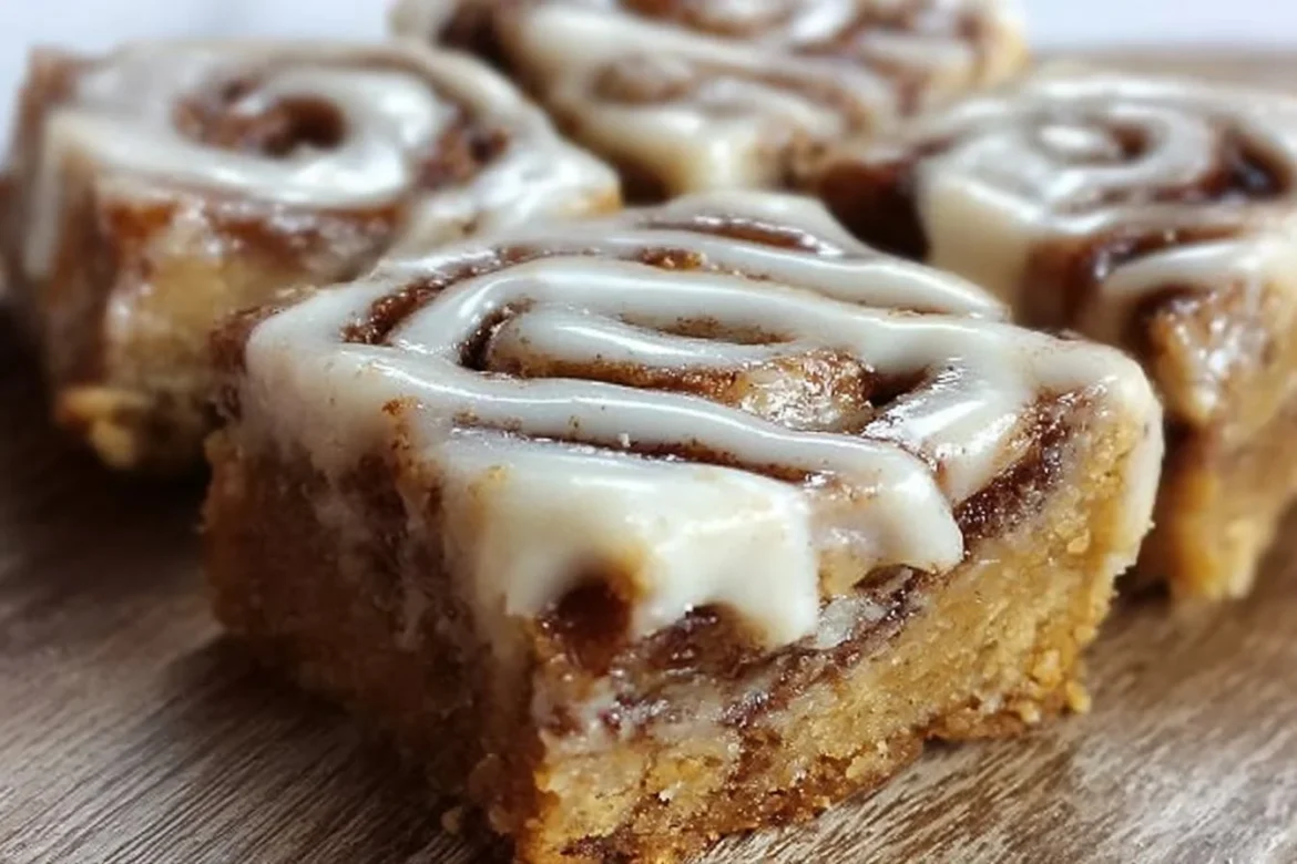 Delicious cinnamon roll bliss bars topped with icing on a wooden table