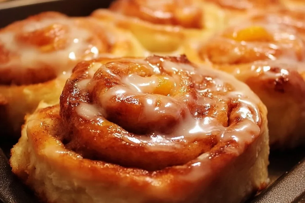 A plate of freshly baked peach pie cinnamon rolls topped with icing.