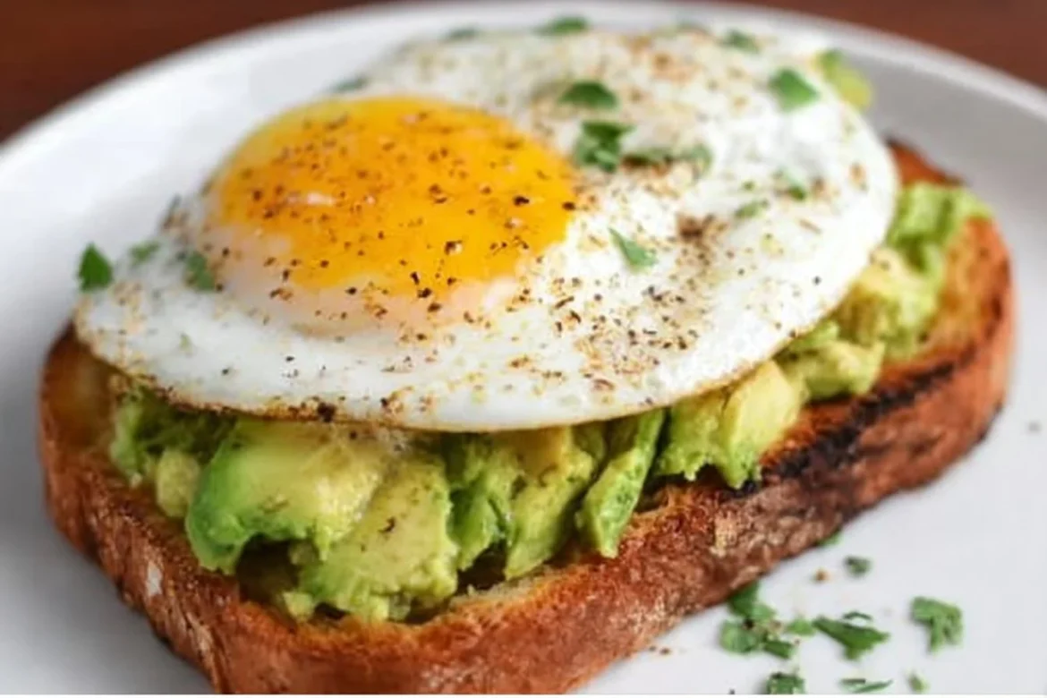 Avocado toast topped with an egg on a plate, showcasing a healthy breakfast.