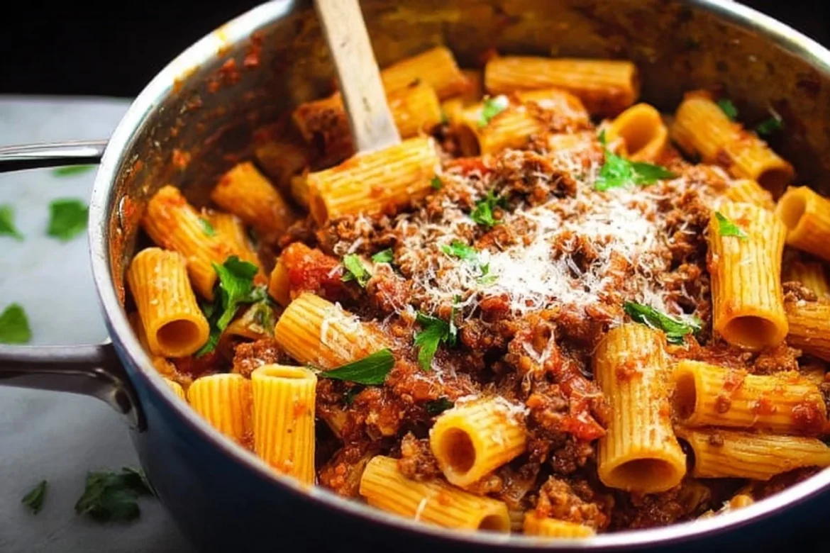 One Pot Rigatoni Bolognese in a skillet with fresh herbs and parmesan cheese
