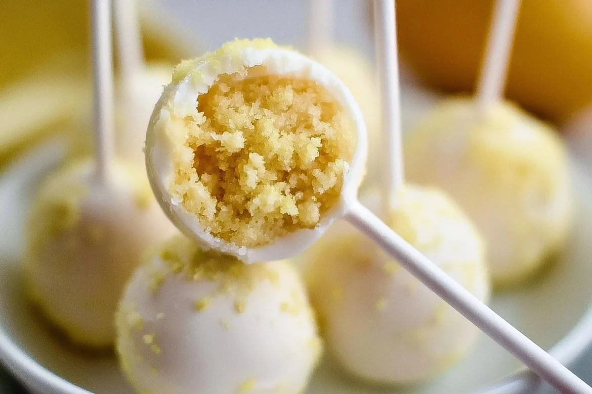 Lemon cake pops on sticks, decorated with yellow sprinkles, on a white plate.