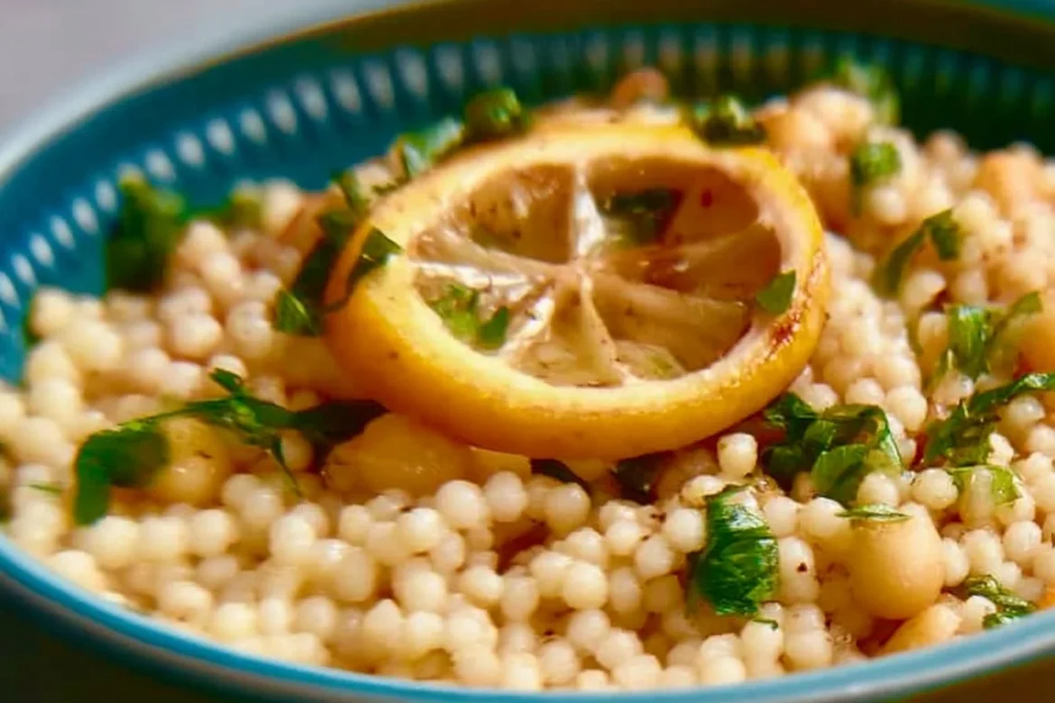 Bowl of Lemon Butter Pearl Couscous topped with herbs and lemon slices