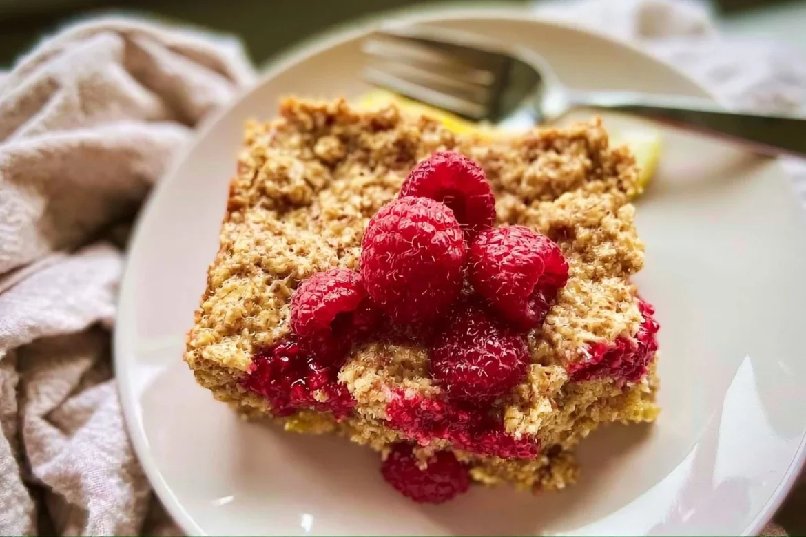 Dish of lemon raspberry baked oatmeal topped with fresh raspberries and lemon zest.