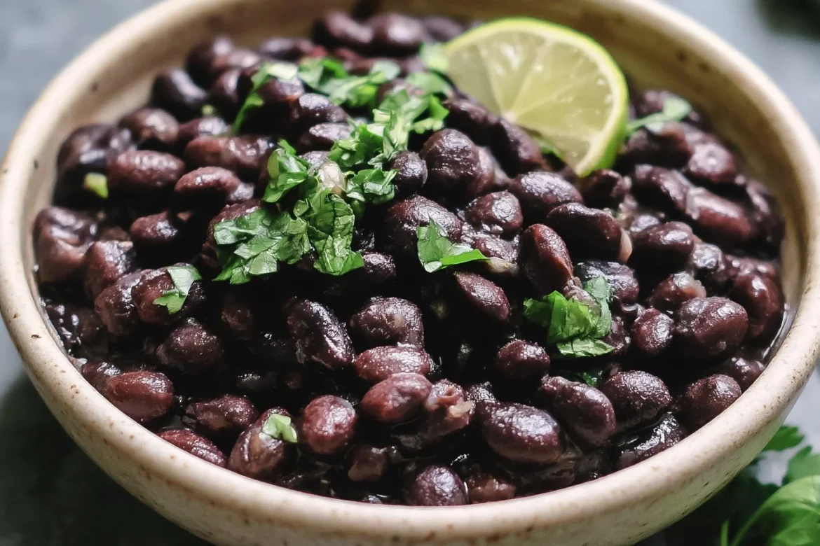 Bowl of seasoned Mexican black beans garnished with cilantro and lime