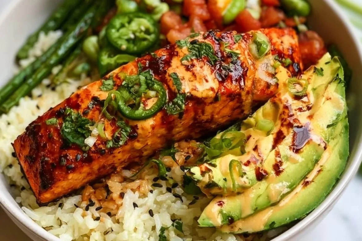 Baked chili lime salmon bowl garnished with fresh vegetables and lime wedges