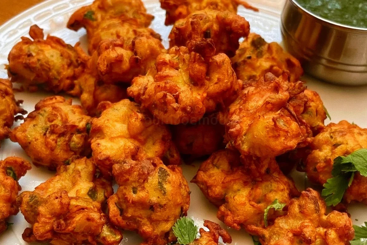 Plate of crispy Pakora Indian vegetable fritters served with dipping sauce
