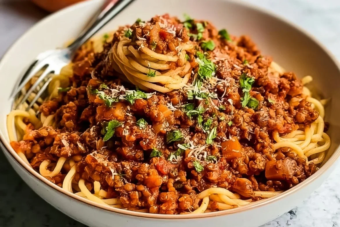 A bowl of Vegan Lentil Bolognese topped with fresh herbs and served with pasta